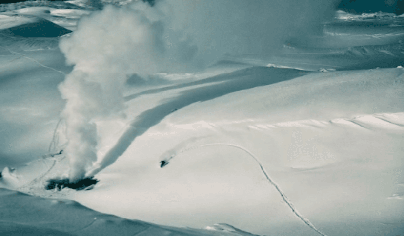 Backcountry snowboarding in Hokkaido powder, featuring a snowboarder carving fresh tracks near a volcanic steam vent on pristine snow-covered terrain in Japan's premier winter destination. Experience world-class powder skiing and snowboarding in Hokkaido's legendary deep snow conditions.