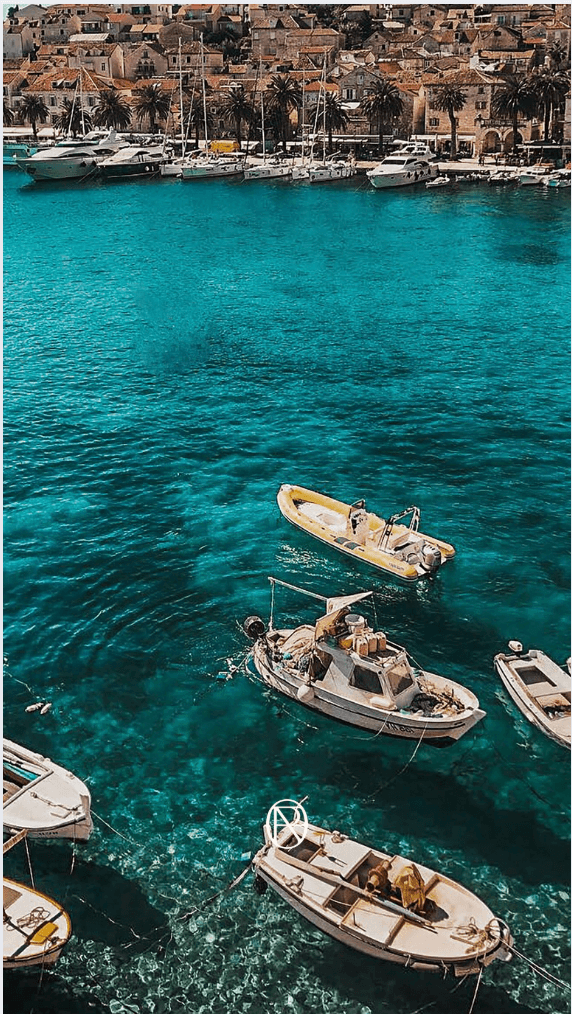 Stunning turquoise waters of the Adriatic Sea with small boats and historic coastal town - perfect Croatia honeymoon itinerary destination with crystal-clear waters and charming Mediterranean architecture